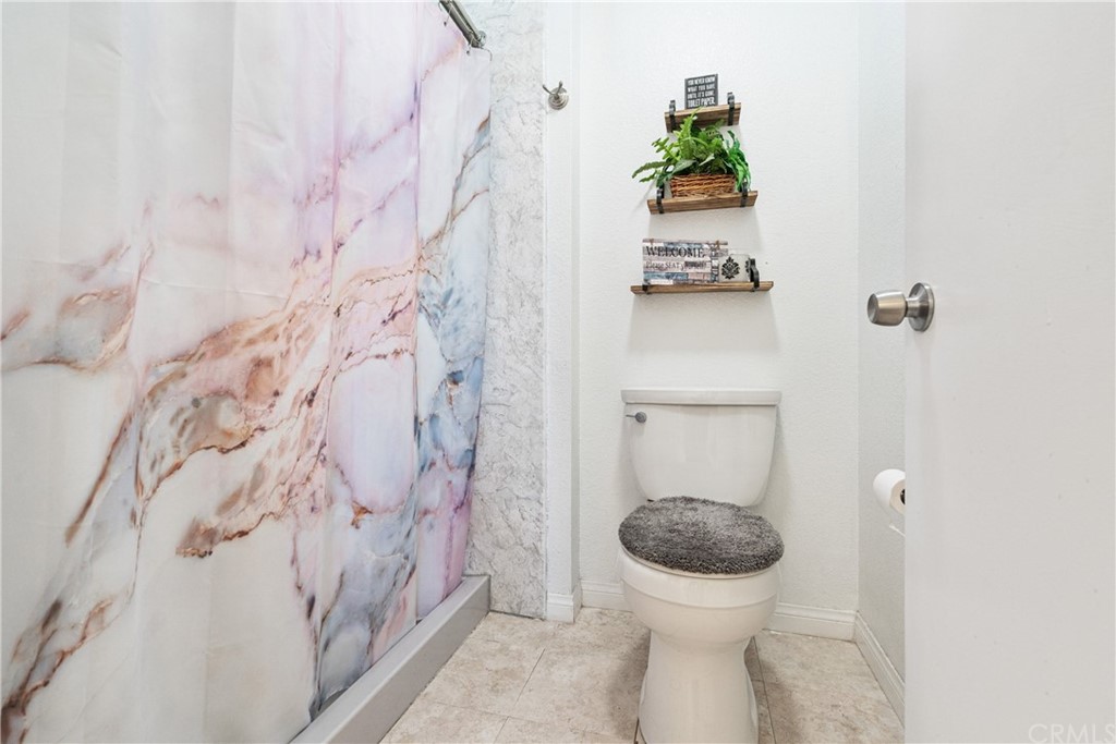 782 De La Luz Circle Perris, CA 92571 - Photo 20 of 25 a bathroom with a toilet and a shower curtain