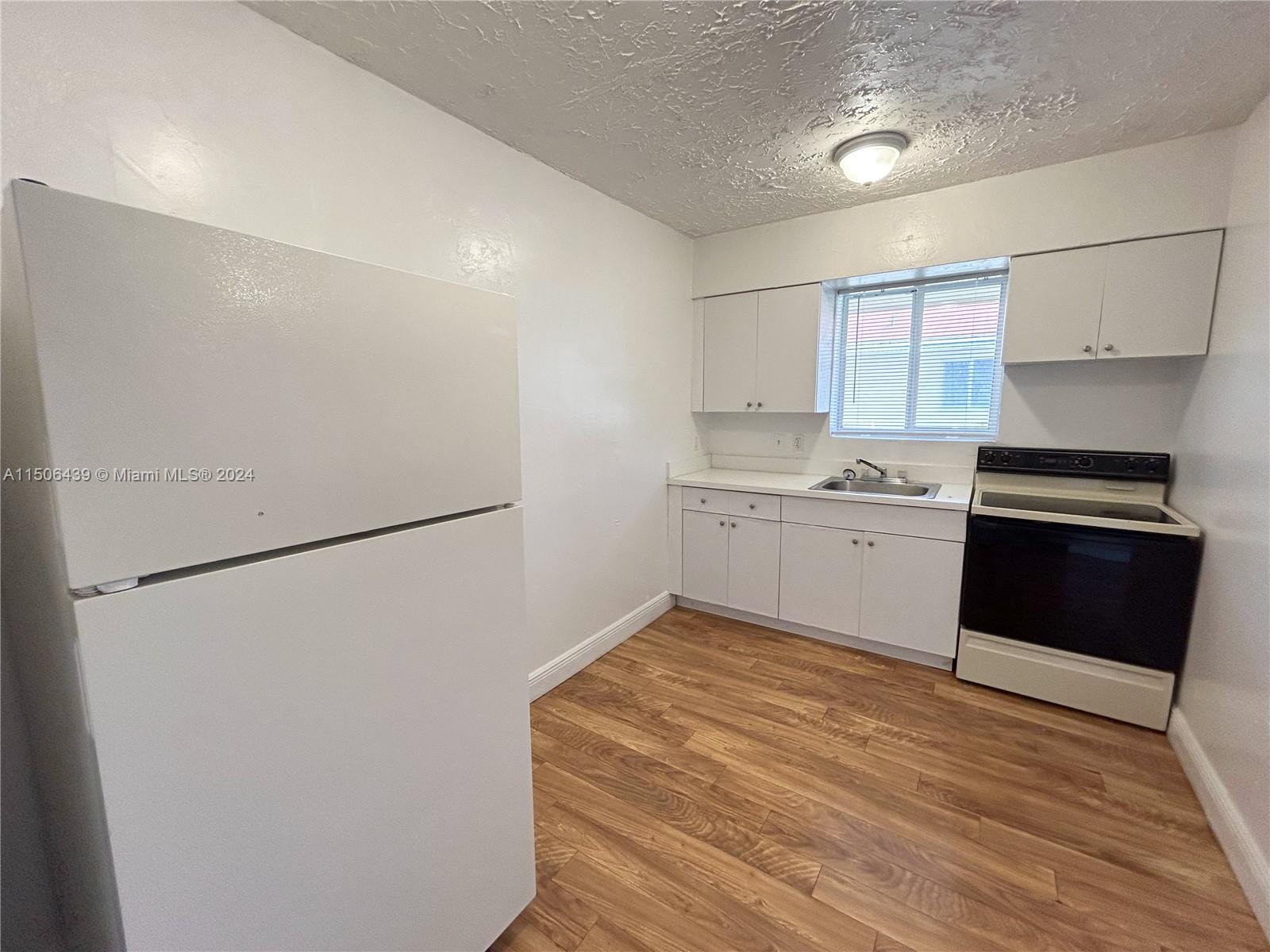 641 Northeast 86th Street, Unit 3 Miami, FL 33138 - Photo 1 of 10 a kitchen with a sink a stove a refrigerator and cabinets