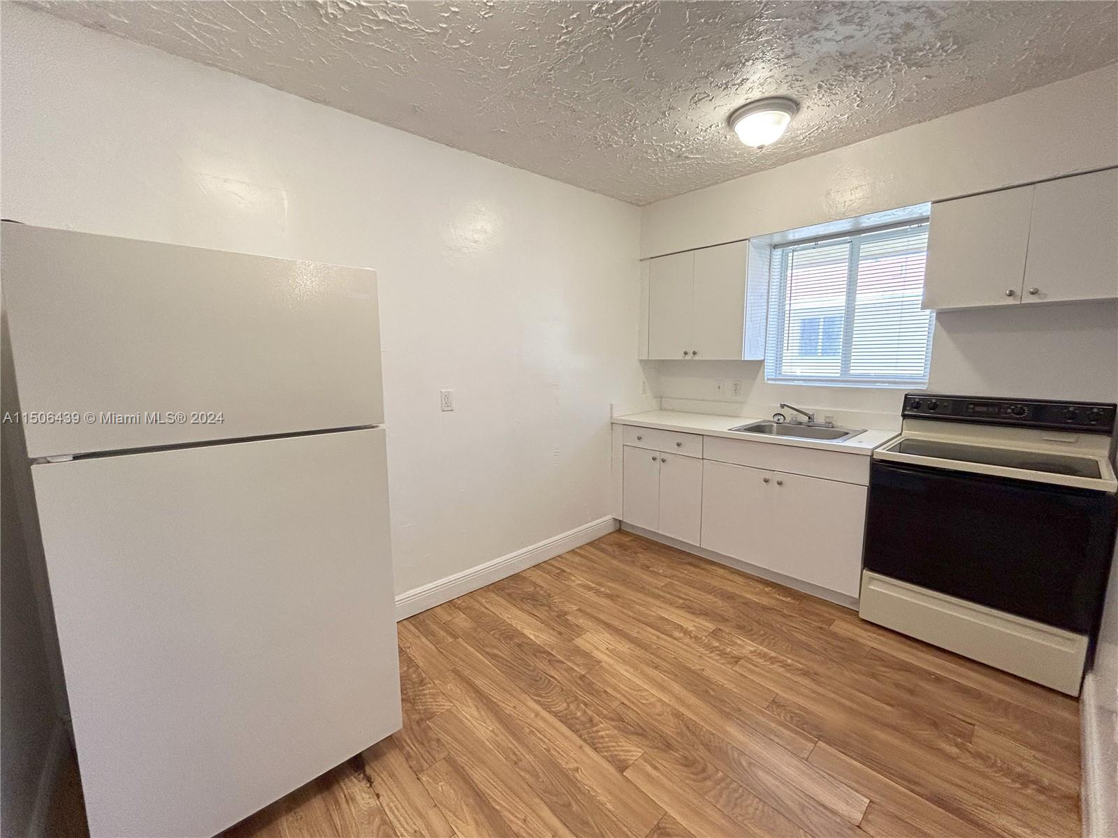 641 Northeast 86th Street, Unit 3 Miami, FL 33138 - Photo 3 of 10 a kitchen with a refrigerator and a stove top oven