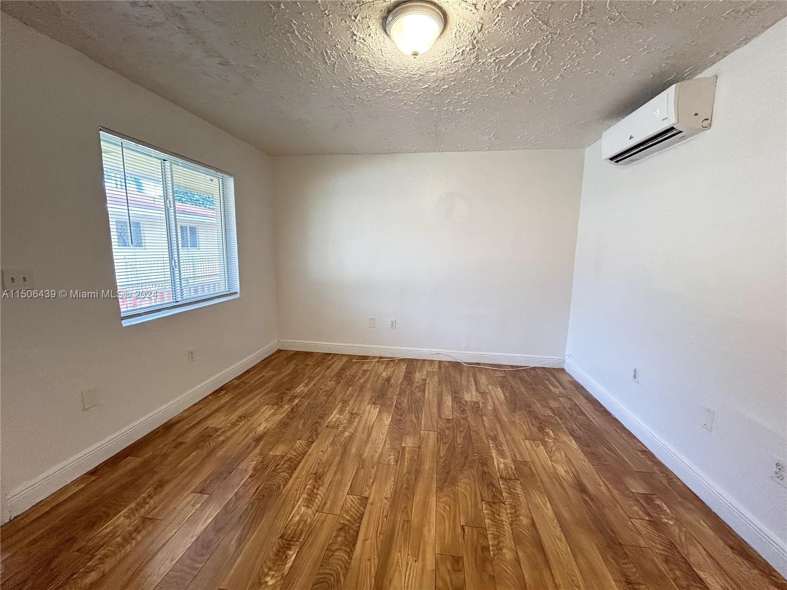 641 Northeast 86th Street, Unit 3 Miami, FL 33138 - Photo 5 of 10 an empty room with wooden floor and windows