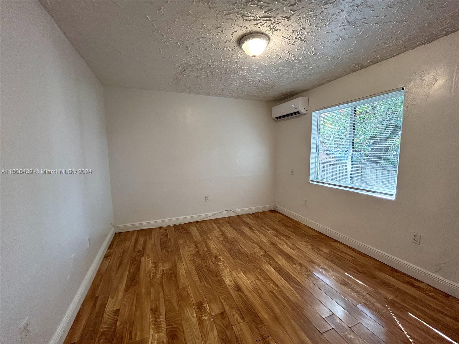 641 Northeast 86th Street, Unit 3 Miami, FL 33138 - Photo 6 of 10 wooden floor in an empty room with a window