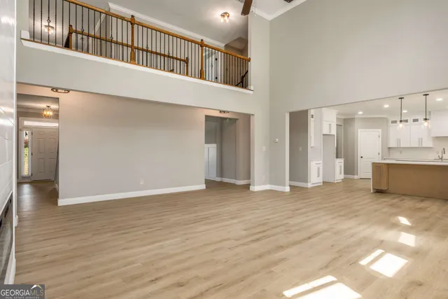 a view of an empty room with wooden floor and a kitchen