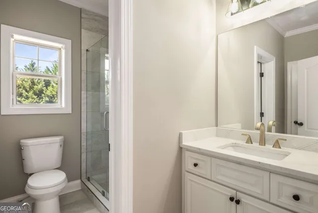 a bathroom with a toilet a sink a mirror and a window