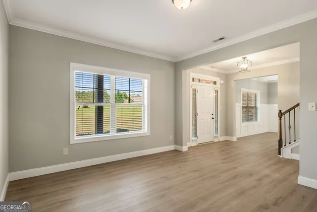 a view of empty room with wooden floor and fan