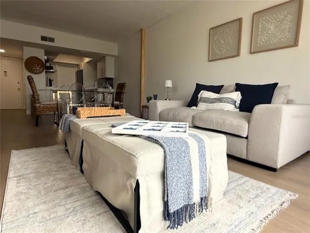 a living room with large couches and kitchen view with wooden floor