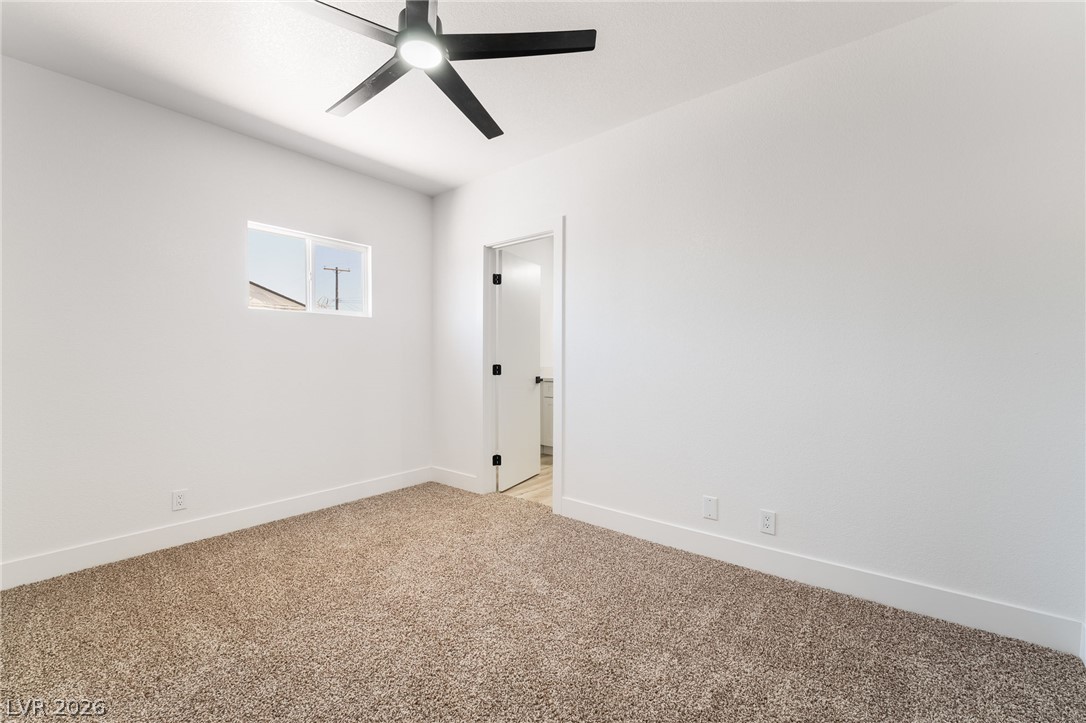 39 Lowery Street Henderson, NV 89015 - Photo 17 of 40 A well-lit bedroom features plush carpeting, a modern ceiling fan, and a view of the outdoors.