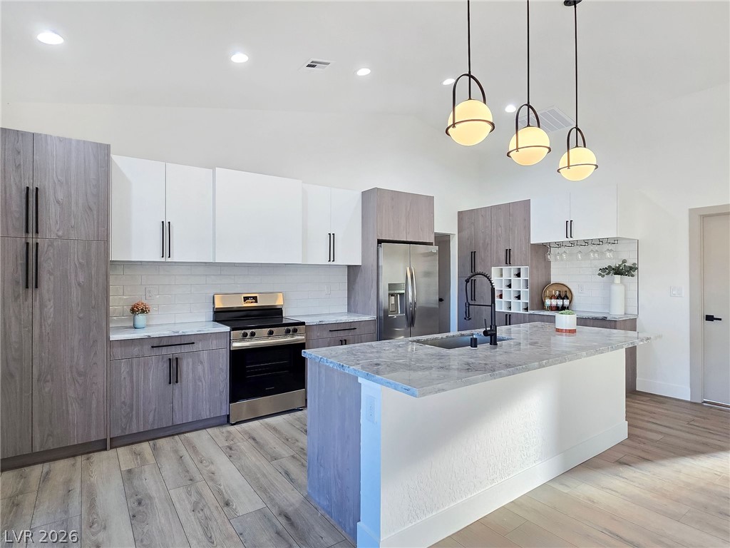 1120 West Gamebird Road Pahrump, NV 89048 - Photo 16 of 36 Kitchen featuring decorative backsplash, white cabinets, pendant lighting, stainless steel appliances, and modern cabinets