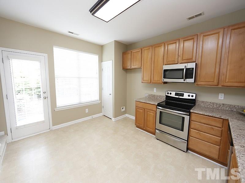8341 City Loft Court Raleigh, NC 27613 - Photo 6 of 19 a kitchen with granite countertop a stove a microwave a sink and cabinets