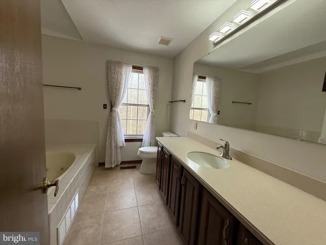 a spacious bathroom with a tub sink shower and mirror