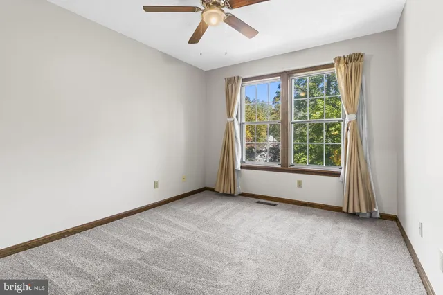 an empty room with a window and a fan