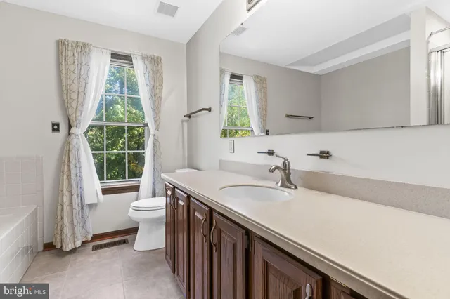 a bathroom with a granite countertop sink a toilet a mirror and a window