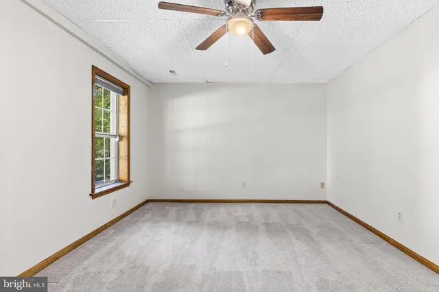 an empty room with a window and a ceiling fan