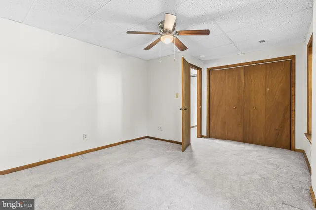 an empty room with a ceiling fan and carpet
