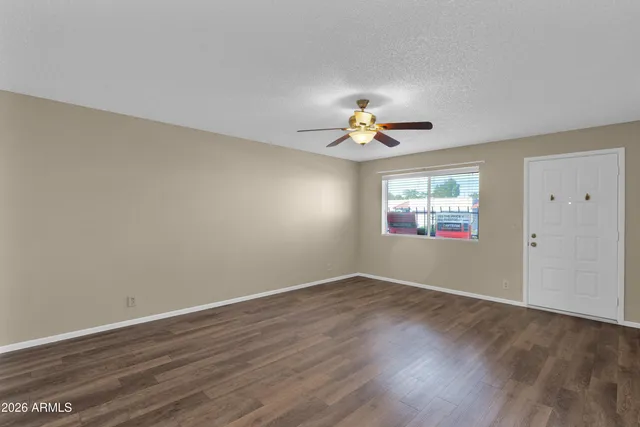 a view of an empty room with a window and wooden floor