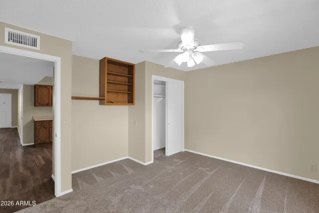 an empty room with closet and a chandelier fan
