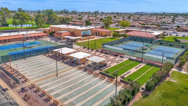 an aerial view of a tennis ground and a cars park side of the road