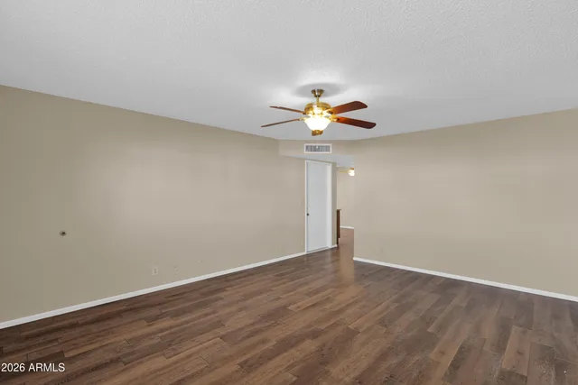 a view of an empty room with a window and wooden floor