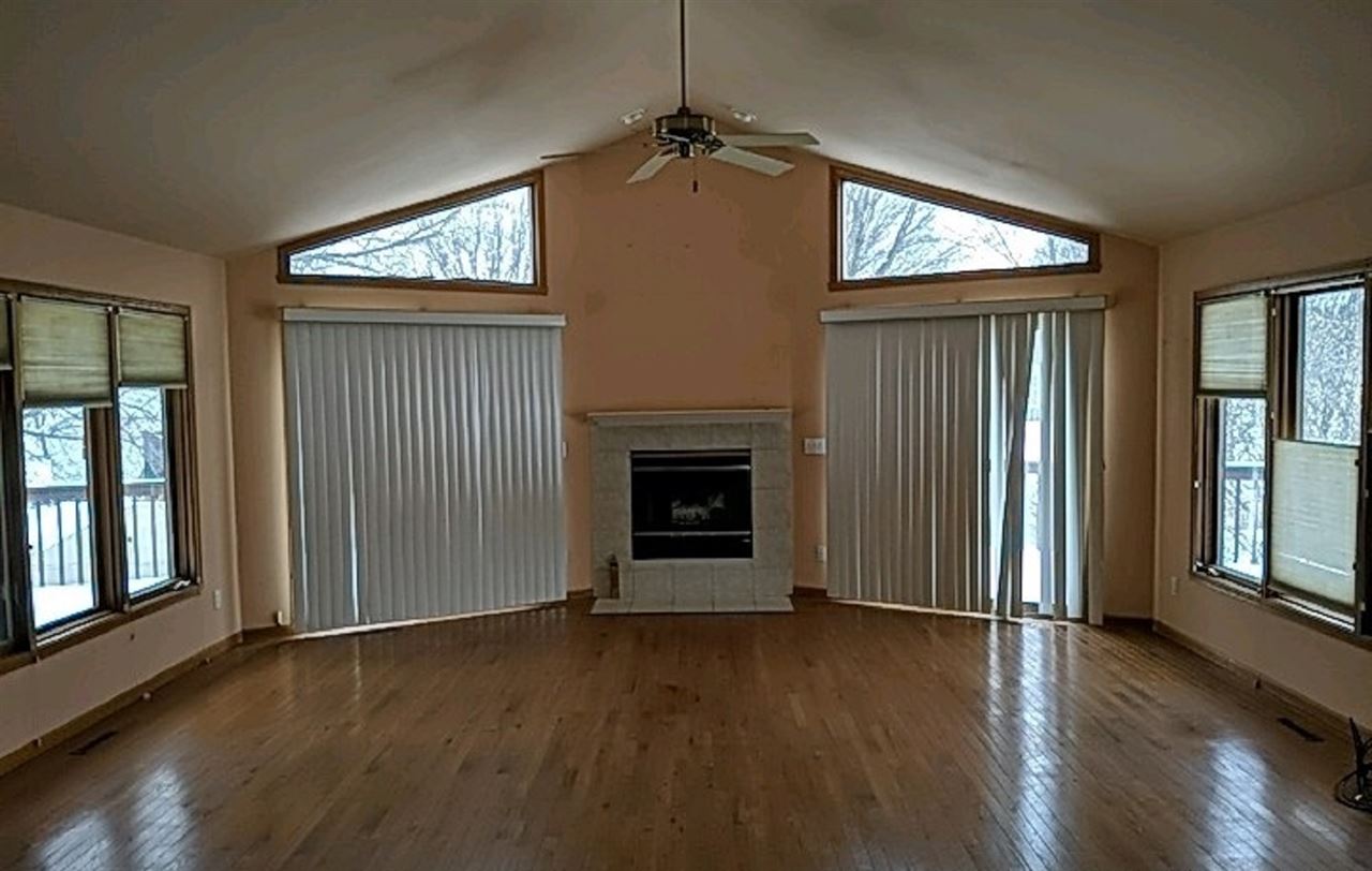 1715 Lake Summerset Road Davis, IL 61019 - Photo 3 of 9 an empty room with wooden floor fireplace and windows