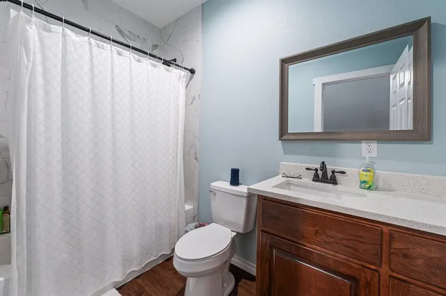 a bathroom with a granite countertop sink toilet and mirror