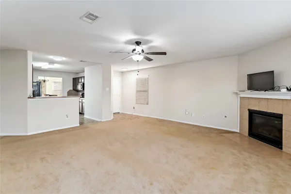 an empty room with a fireplace and chandelier fan