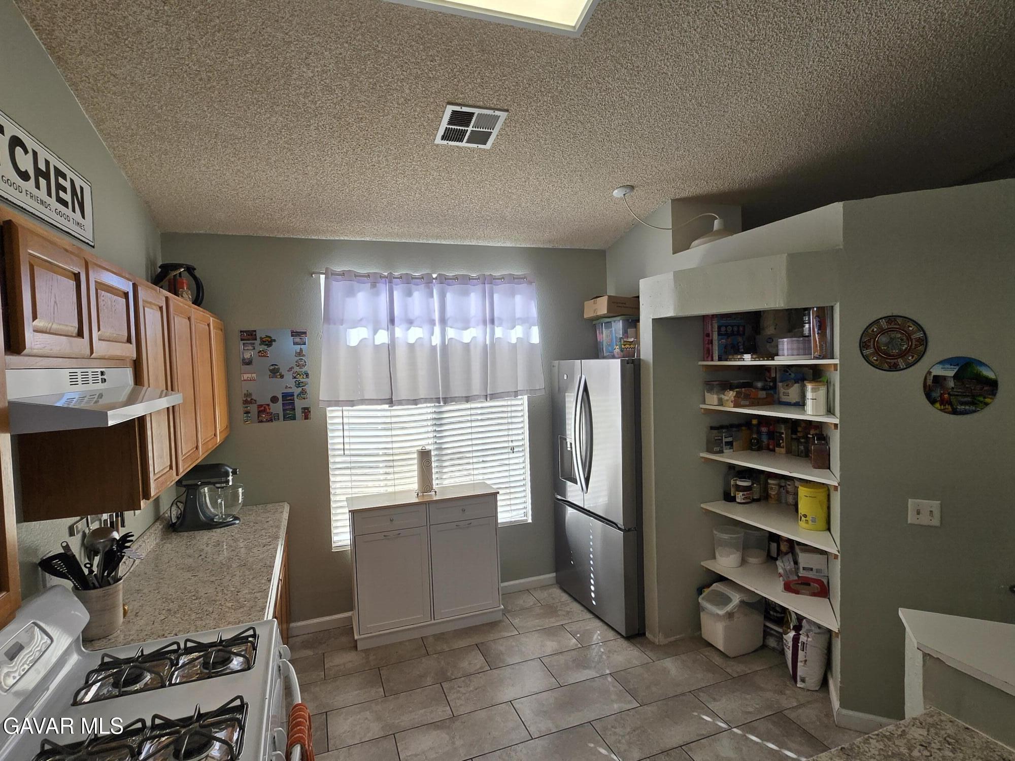 3840 Hatcher Place Rosamond, CA 93560 - Photo 13 of 28 a kitchen with stainless steel appliances a refrigerator and a stove top oven