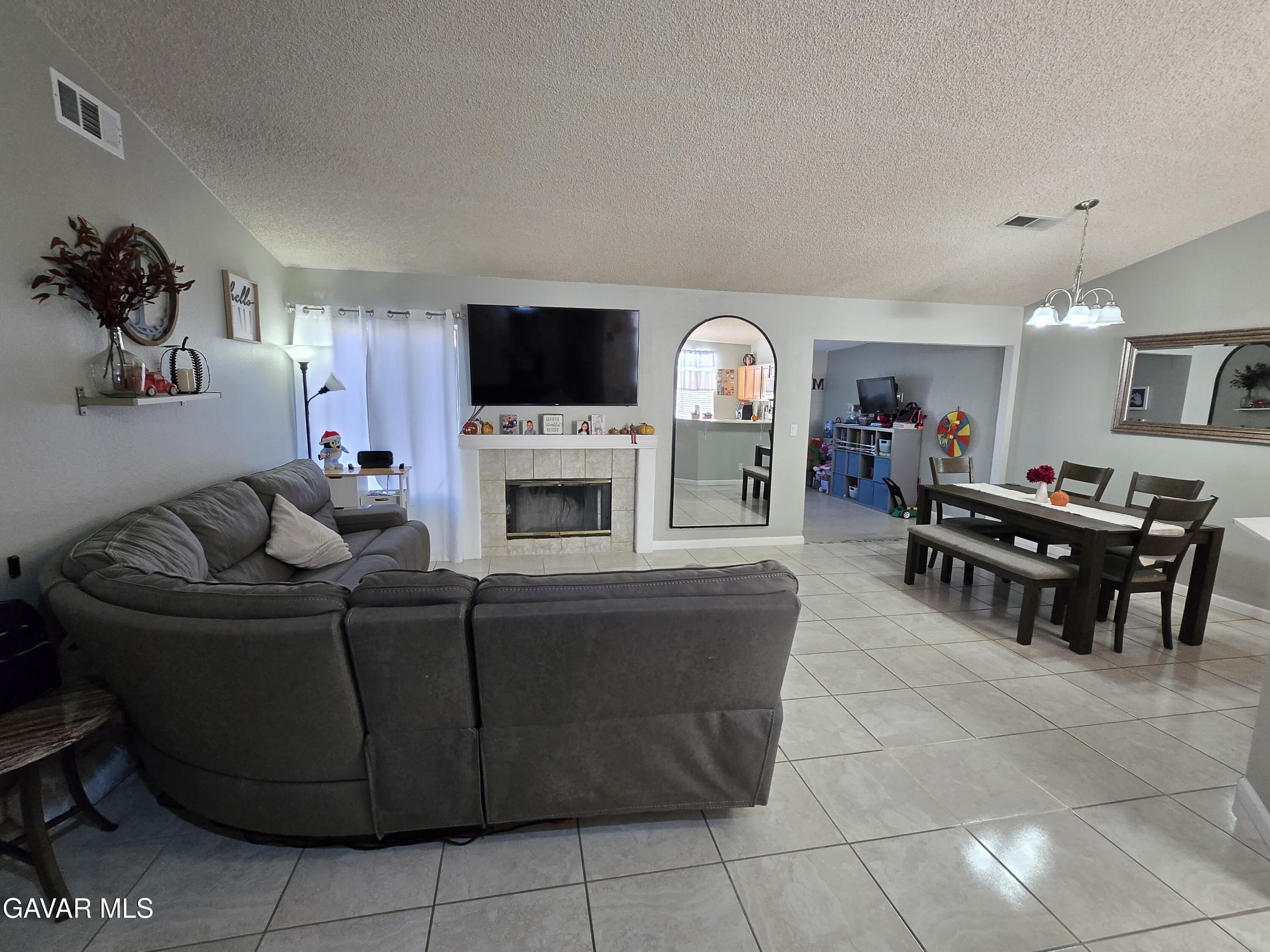 3840 Hatcher Place Rosamond, CA 93560 - Photo 4 of 28 a living room with furniture a flat screen tv and a fireplace