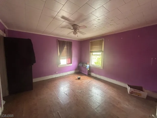 an empty room with windows and fan