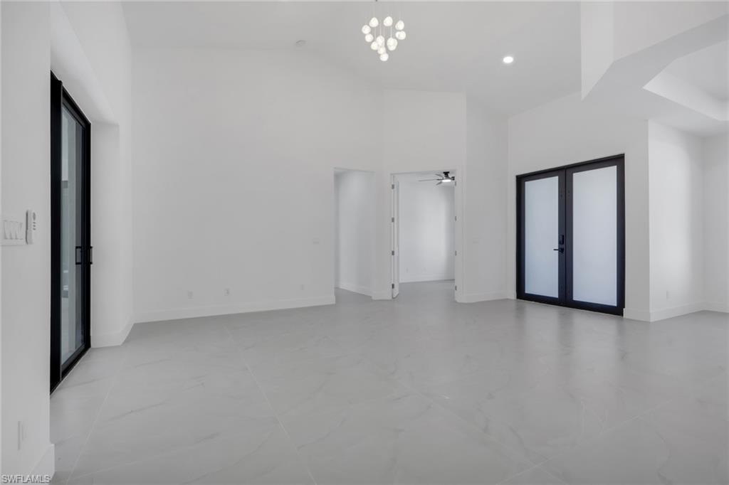 730 29th Street Southwest Naples, FL 34117 - Photo 14 of 50 Unfurnished room with french doors, a high ceiling, a ceiling fan, and hanging lights