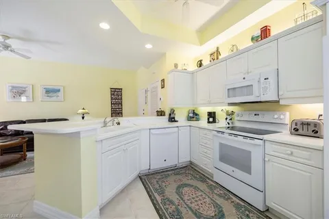 a kitchen with white cabinets sink and stove