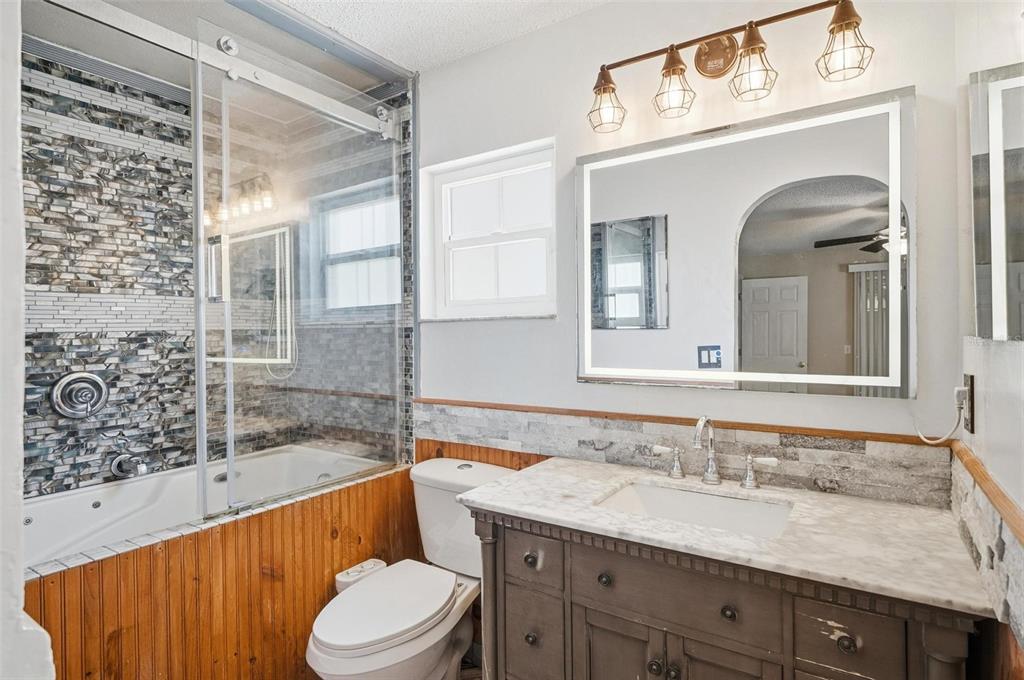 1071 Angora Street Deltona, FL 32725 - Photo 12 of 45 a bathroom with a granite countertop sink vanity mirror bathtub shower and toilet