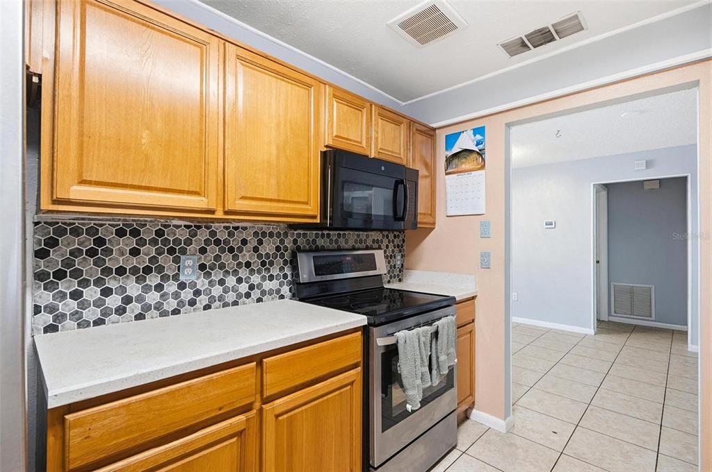1071 Angora Street Deltona, FL 32725 - Photo 7 of 45 a kitchen with stainless steel appliances granite countertop a stove a sink and a microwave