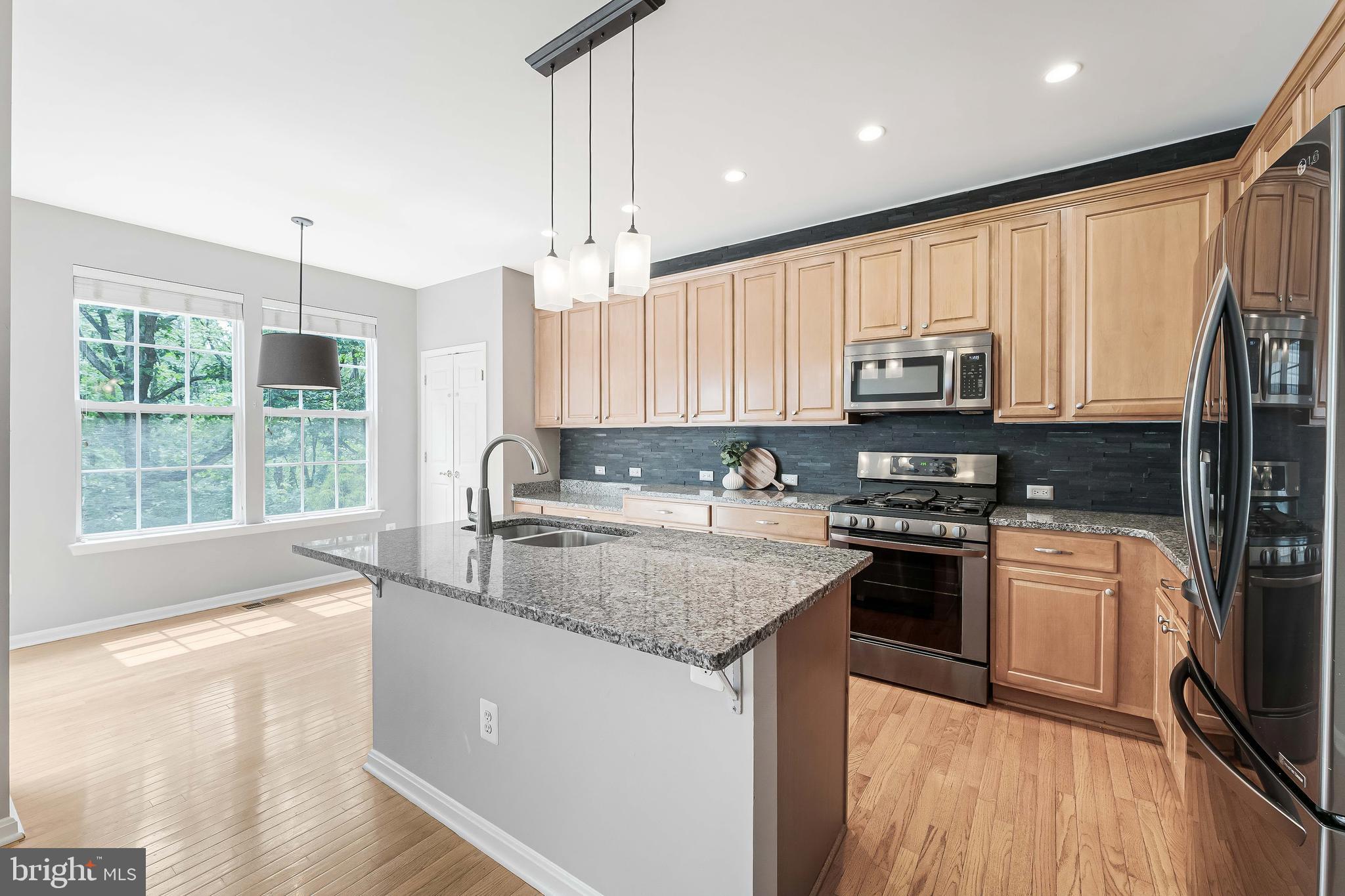 43103 Forest Edge Square Broadlands, VA 20148 - Photo 11 of 57 a kitchen with stainless steel appliances granite countertop a stove a sink and a microwave