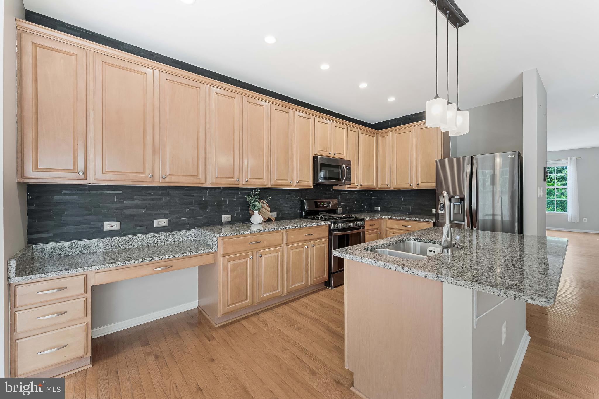 43103 Forest Edge Square Broadlands, VA 20148 - Photo 18 of 57 a kitchen with kitchen island granite countertop wooden cabinets and white appliances