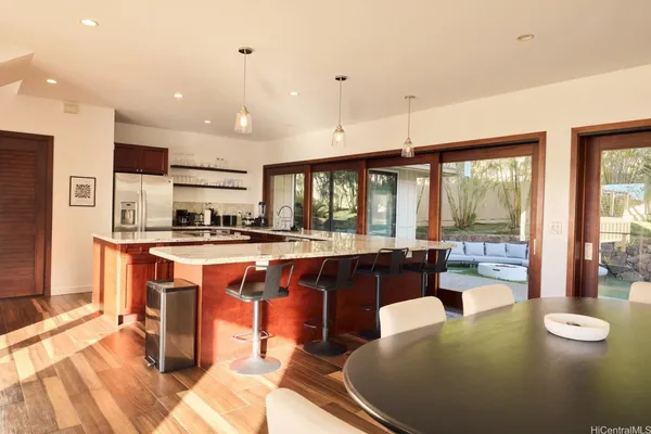 a kitchen with stainless steel appliances granite countertop a stove a refrigerator a sink a dining table and chairs with wooden floor