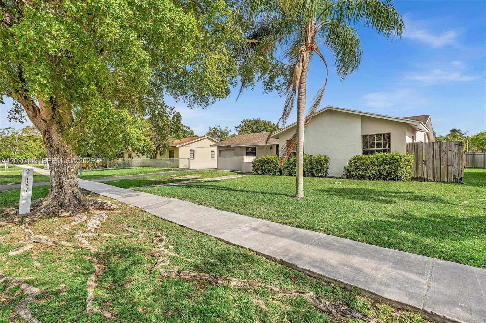 11061 Southwest 163rd Street Miami, FL 33157 - Photo 2 of 42 a view of a house with a yard and palm trees