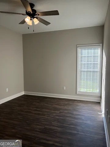 an empty room with wooden floor chandelier fan and windows