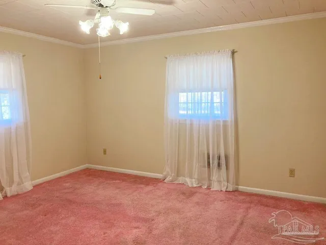 an empty room with a chandelier fan and windows