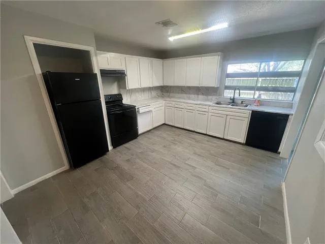 a kitchen with a sink a refrigerator a microwave and cabinets