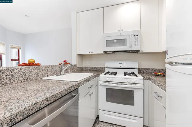 a kitchen with granite countertop white cabinets and white appliances