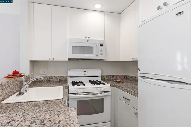 a kitchen with stainless steel appliances granite countertop a sink stove top oven and cabinets