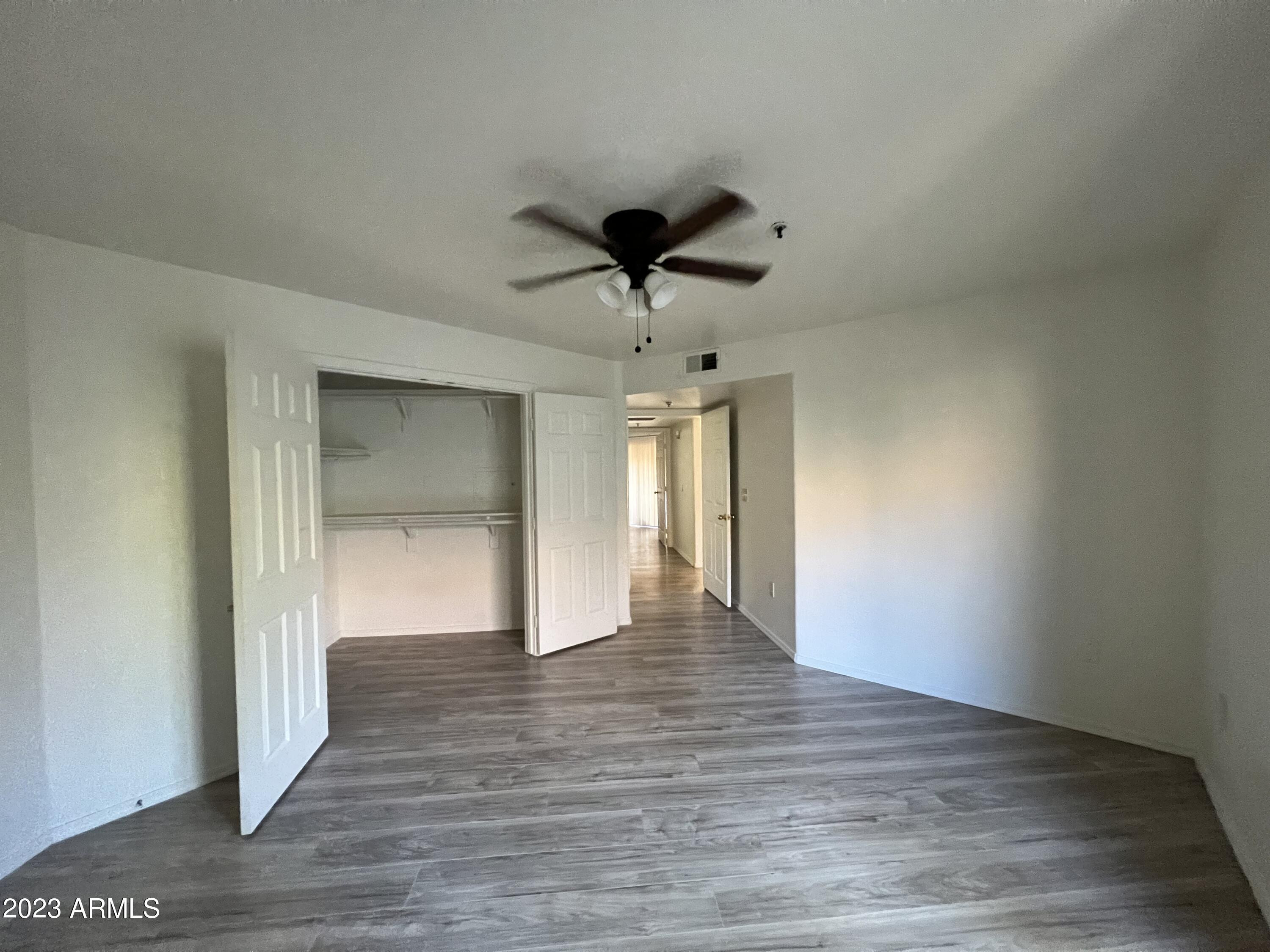 1287 North Alma School Road, Unit 224 Chandler, AZ 85224 - Photo 4 of 8 a view of an empty room and wooden floor and a ceiling fan