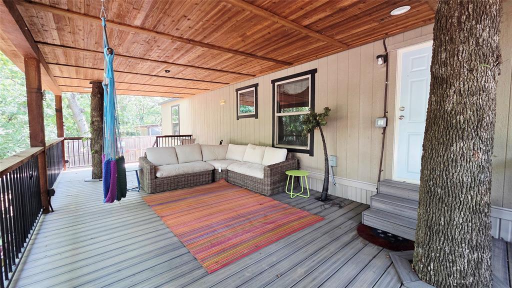 45 Bravo Road Pottsboro, TX 75076 - Photo 3 of 40 Spacious covered deck featuring a natural wood plank ceiling, light-colored vertical siding, and grey wood-finish flooring