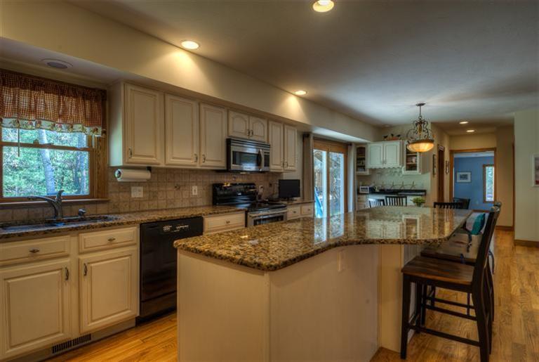 200 Evergreen Drive Marstons Mills, MA 02648 - Photo 4 of 25 a kitchen with kitchen island granite countertop a stove top oven a sink a dining table and chairs with wooden floor