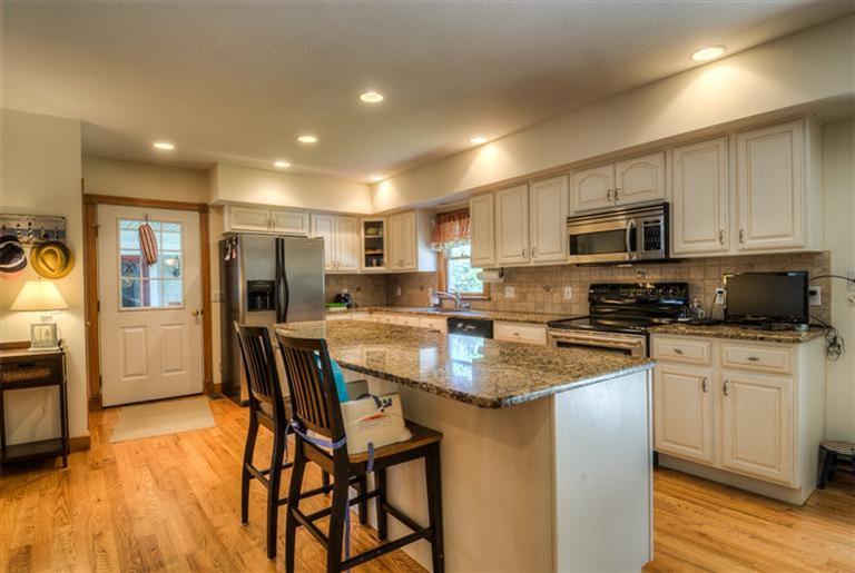 200 Evergreen Drive Marstons Mills, MA 02648 - Photo 5 of 25 a kitchen with stainless steel appliances granite countertop a stove a sink a microwave a refrigerator white cabinets and wooden floor