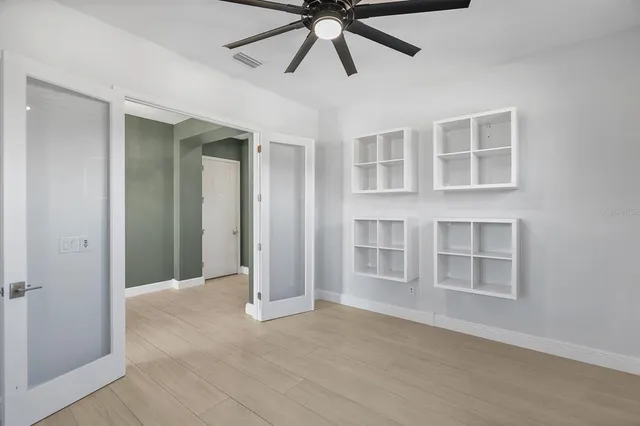 a view of n empty room with window and chandelier fan