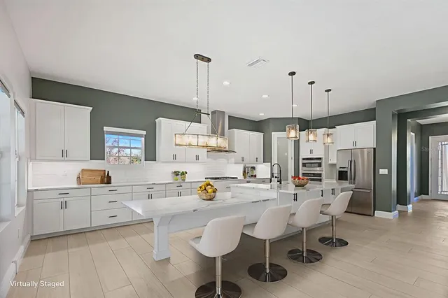 a large white kitchen with kitchen island a large window and stainless steel appliances