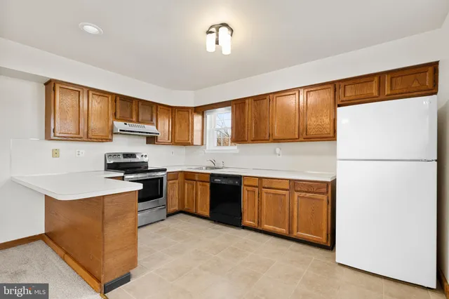 a kitchen with granite countertop a refrigerator stove top oven a sink and dishwasher