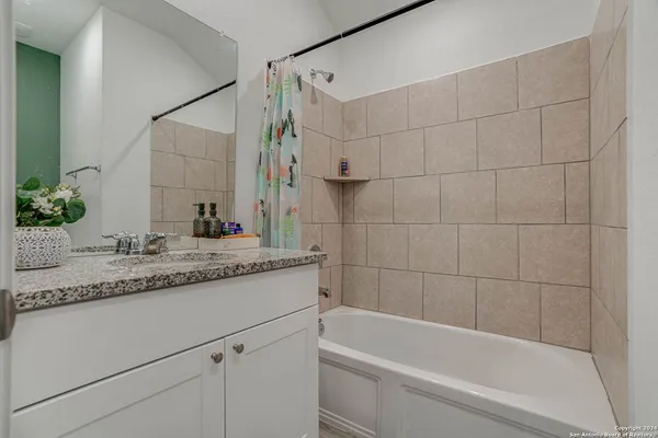 a bathroom with a granite countertop bathtub sink vanity and toilet