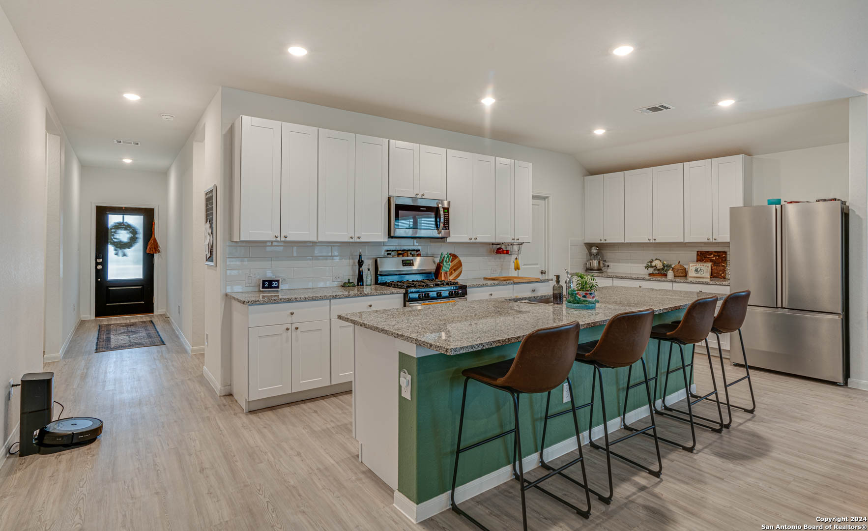 14606 Somerset Mill San Antonio, TX 78254 - Photo 3 of 19 a kitchen with granite countertop a refrigerator a stove a sink a dining table and chairs with wooden floor