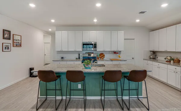 a kitchen with stainless steel appliances granite countertop a stove a sink a stove a dining table and chairs